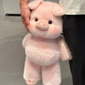 Person holding a pink plush pig toy against a neutral background