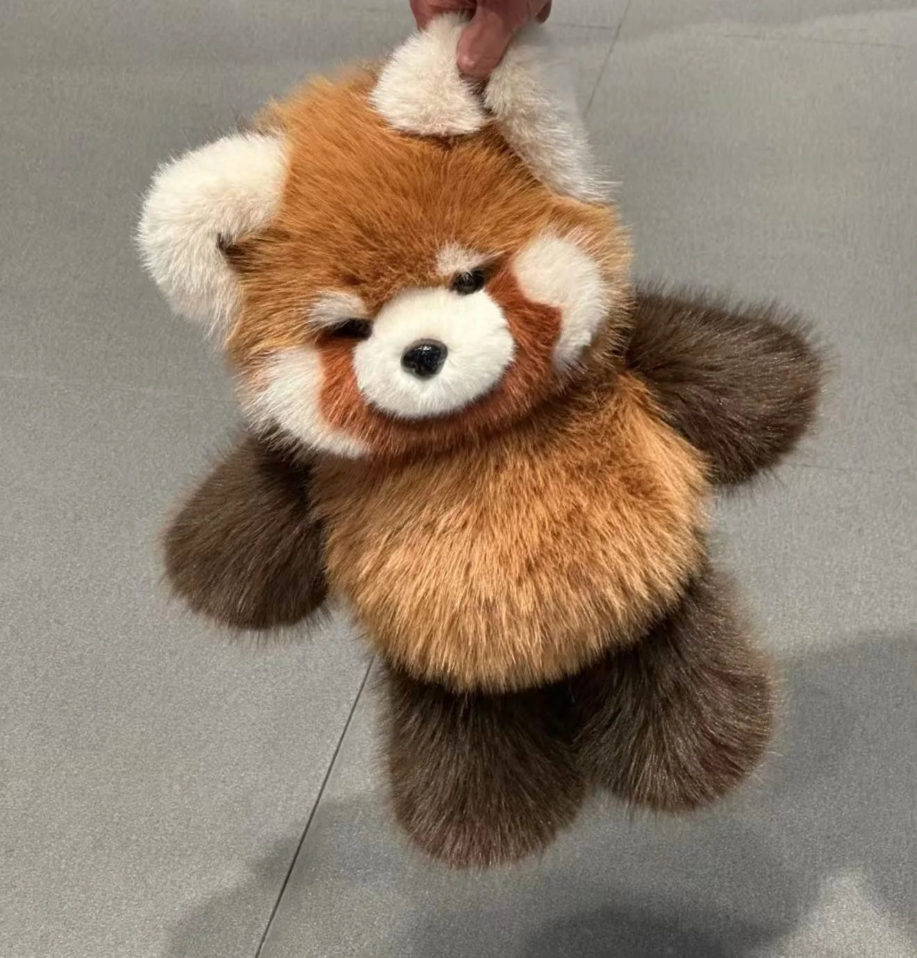 Plush toy resembling a red panda on a gray background