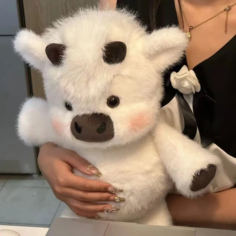 Person holding a white plush cow toy with brown accents