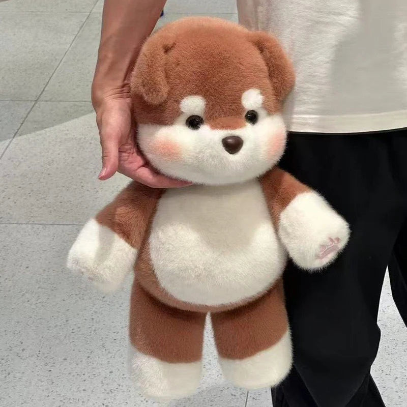 Brown and white plush dog held by a person on a light gray floor.
