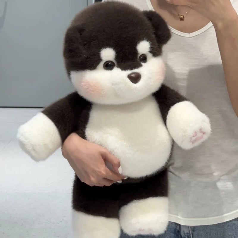 Person holding a black and white plush toy resembling a dog
