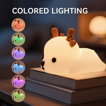 Deer-shaped night light with colored lighting options displayed on a book