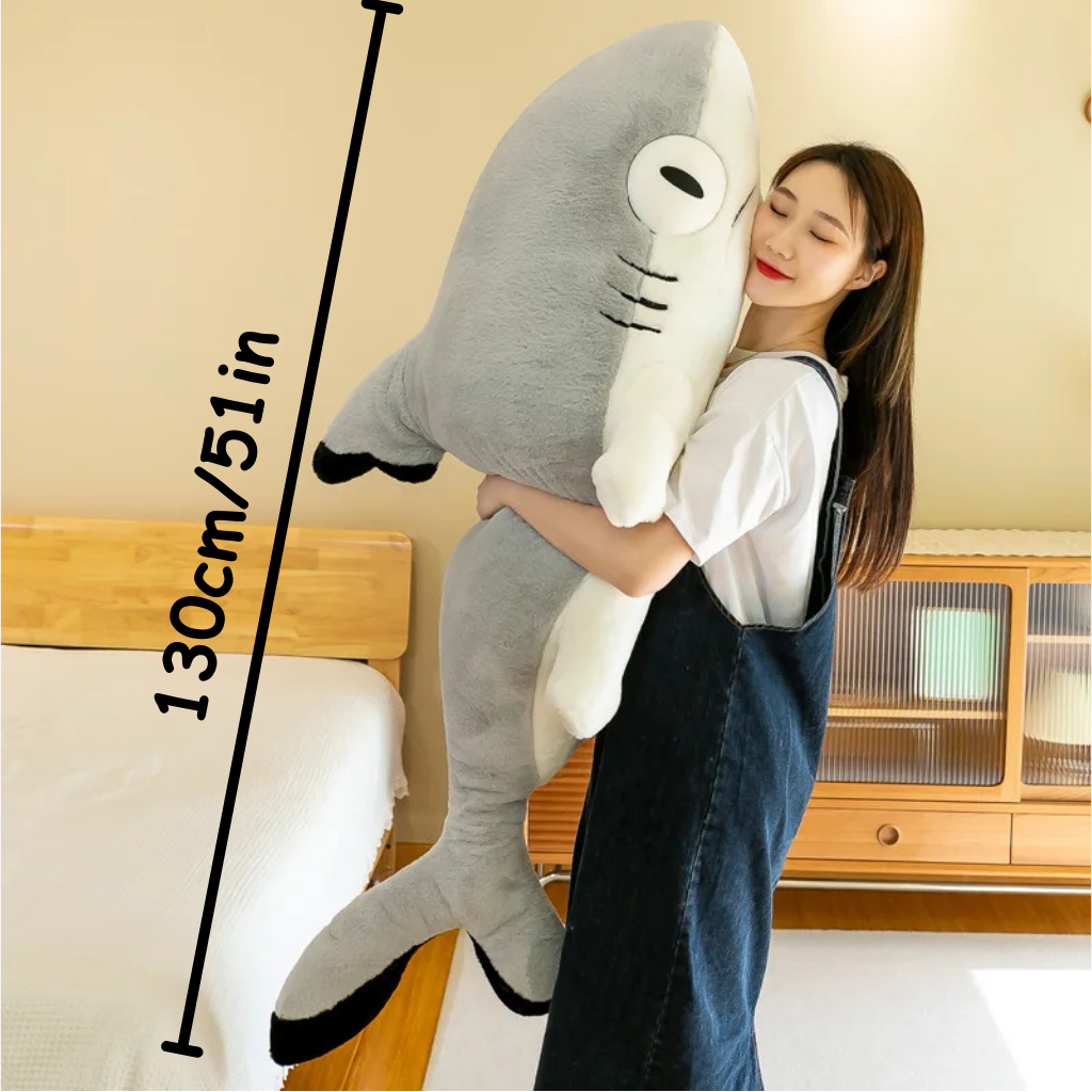 Person holding a large shark-shaped plush toy with a measurement label saying 130cm/51in