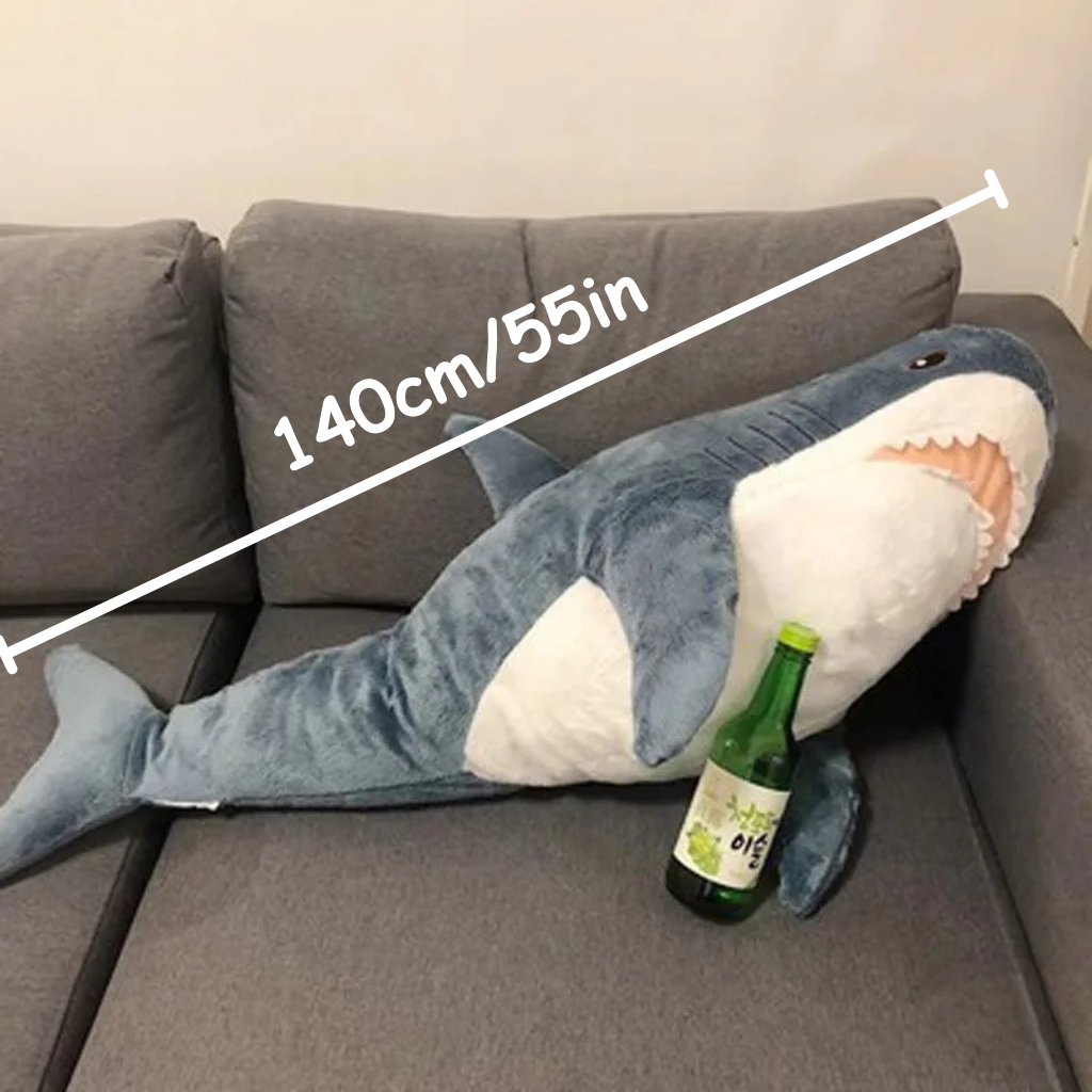 Grote pluche haai op een bank, met afmetingen die 140 cm/55 inch aangeven
